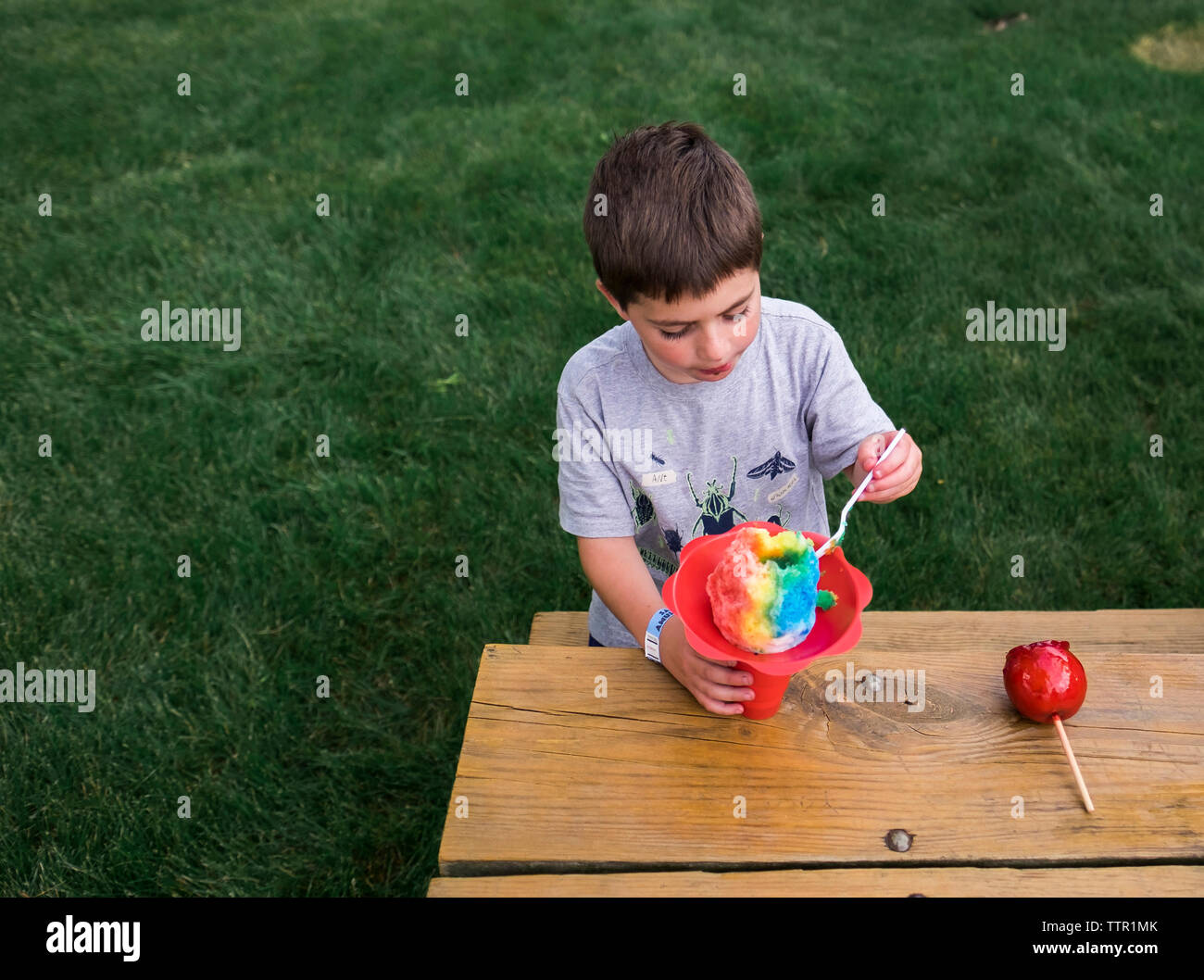Hohe Betrachtungswinkel von Boy aromatisiert Eis essen während sitzt auf der Bank im Park Stockfoto