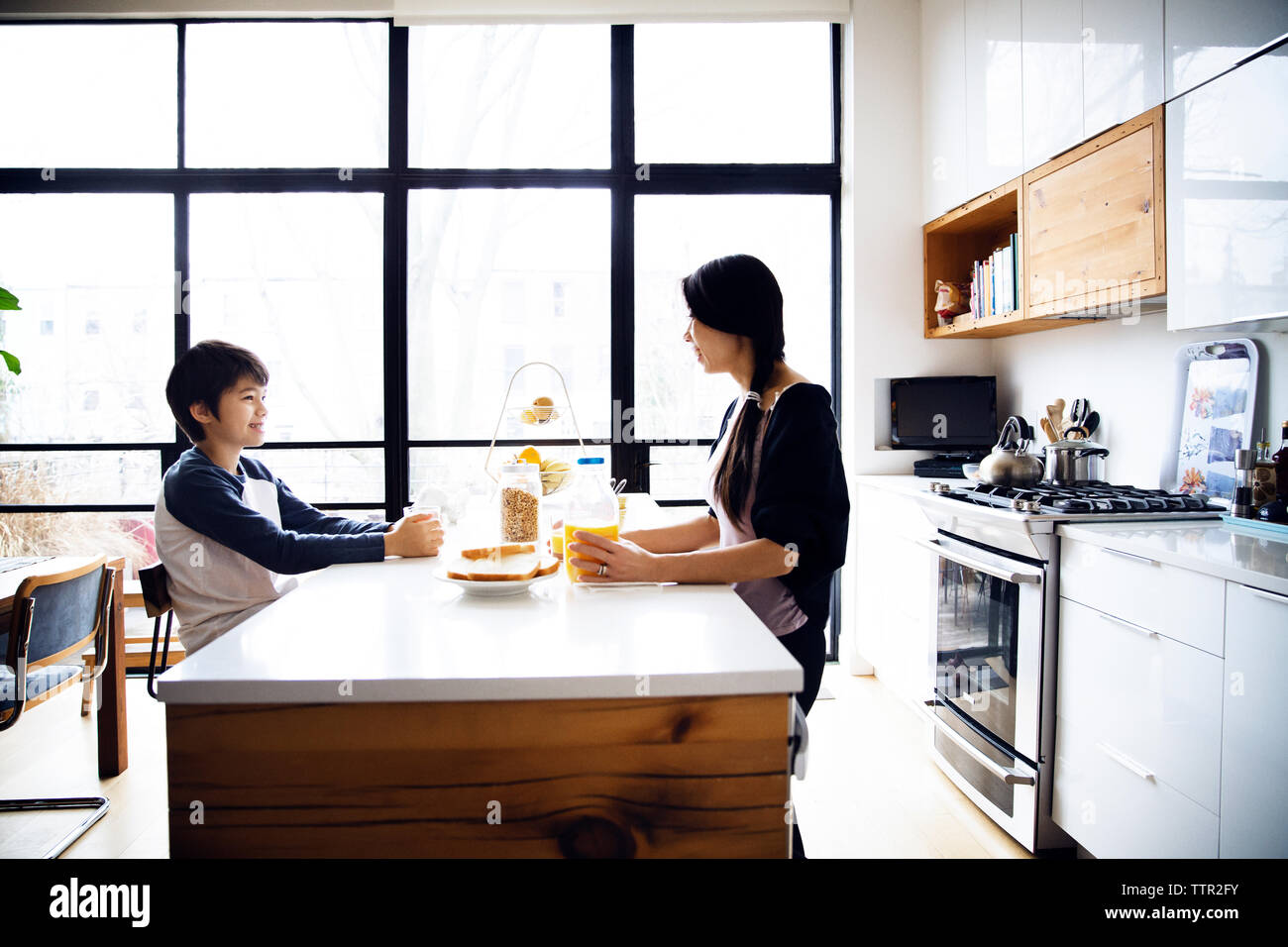 Mutter und Sohn essen Frühstück am Tisch in hell erleuchtete Küche Stockfoto