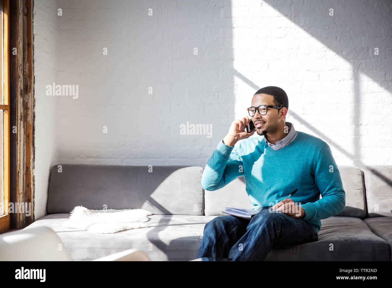 Geschäftsmann, der im Büro auf dem Sofa sitzt Stockfoto