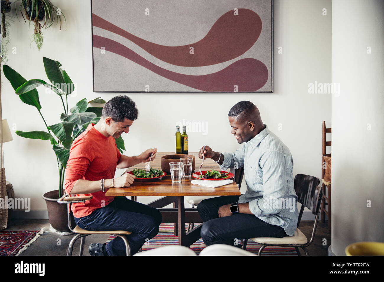 Homosexuelle Männer in frischem Salat am Esstisch Stockfoto