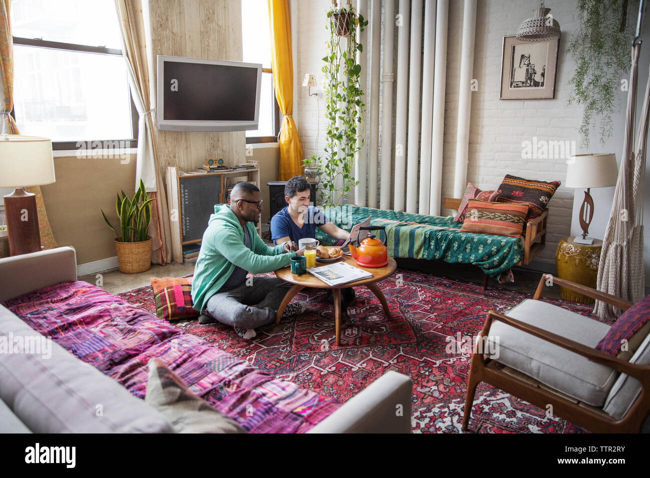 Homosexuelle Männer lesen Zeitung beim Frühstück zu Hause in Stockfoto