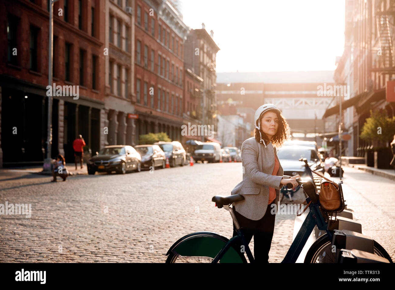 Geschäftsfrau hält Fahrrad auf dem Parkplatz auf der Straße Stockfoto