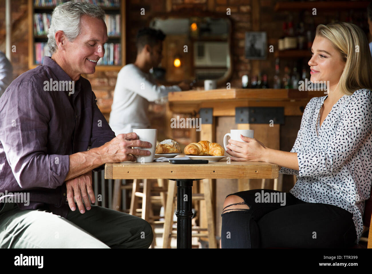 Die Menschen reden, während sie Kaffee und Croissants am Tisch im Cafe Stockfoto