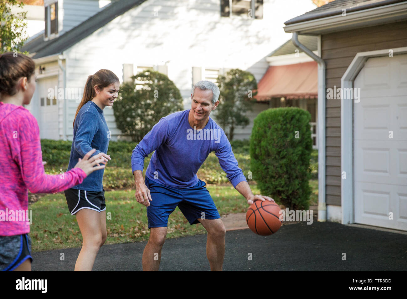 Großvater spielen Basketball mit enkelinnen im Hinterhof Stockfoto