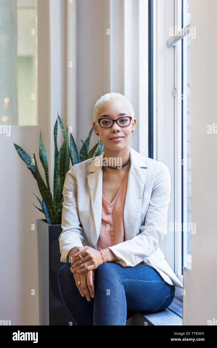 Portrait von zuversichtlich, Geschäftsfrau, sitzen auf der Fensterbank im Büro Stockfoto