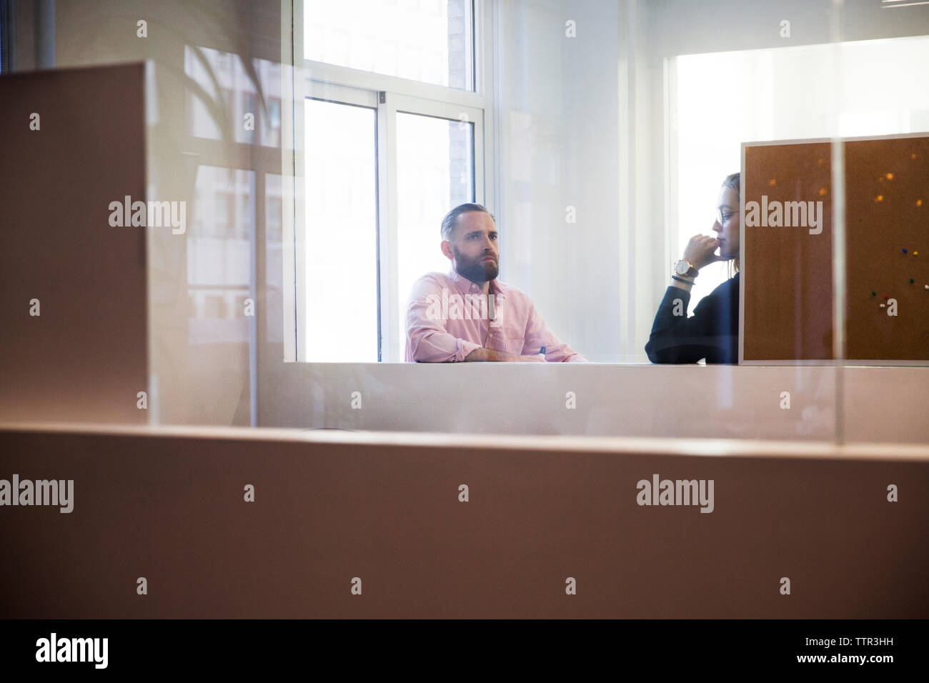 Geschäftsleute, die im Büro planen, durch Glas gesehen Stockfoto