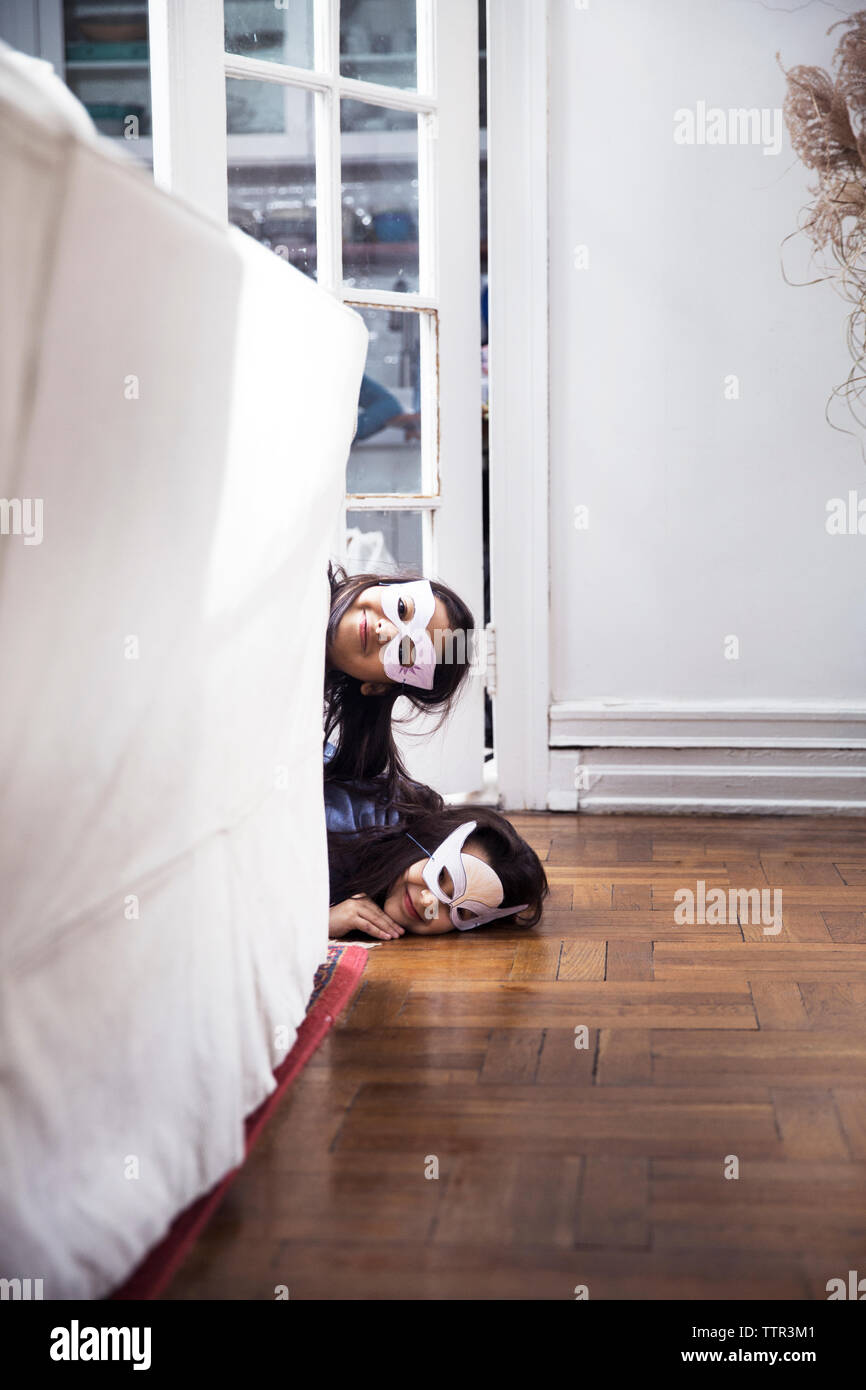 Portrait von Schwestern tragen Augenmasken peeking von Sofa zu Hause Stockfoto