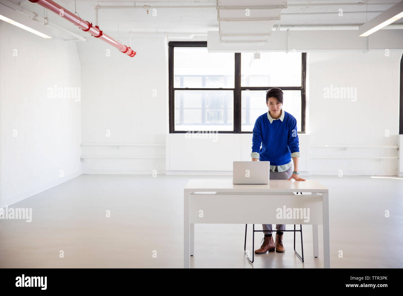 Portrait der Unternehmerin mit Laptop steht die Tabelle im neuen Büro Stockfoto