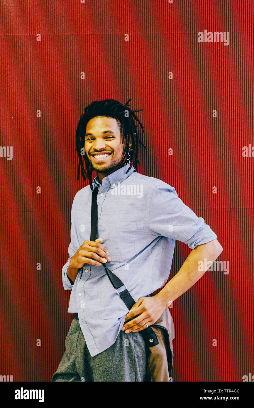 Portrait von Happy Geschäftsmann mit Messenger Bag von Rote Wand in der kreativen Büro Stockfoto