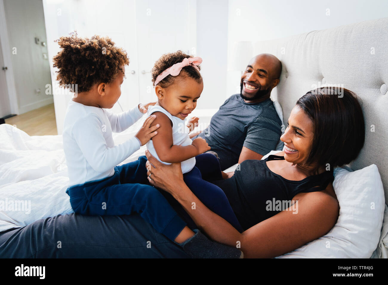 Glückliche Eltern spielen mit den Kindern, während sie sich auf dem Bett zu Hause. Stockfoto