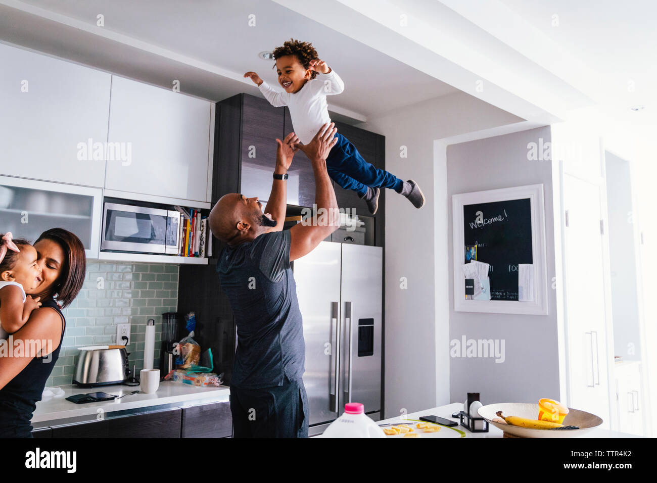 Glückliche Eltern spielen mit den Kindern beim Stehen in der Küche zu Hause Stockfoto