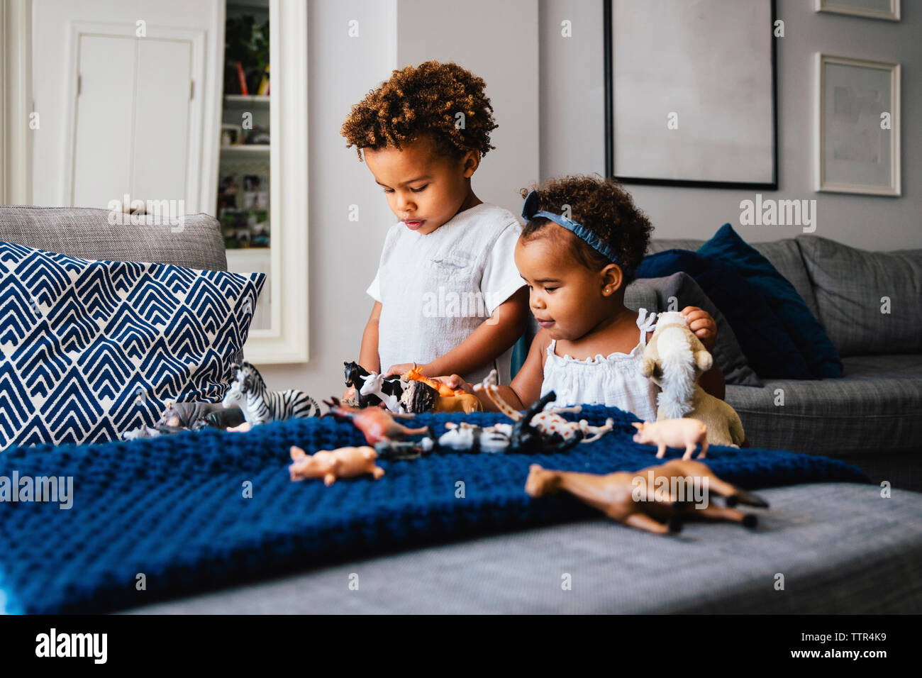 Nette Geschwister mit Spielzeug spielen auf dem Sofa zu Hause Stockfoto