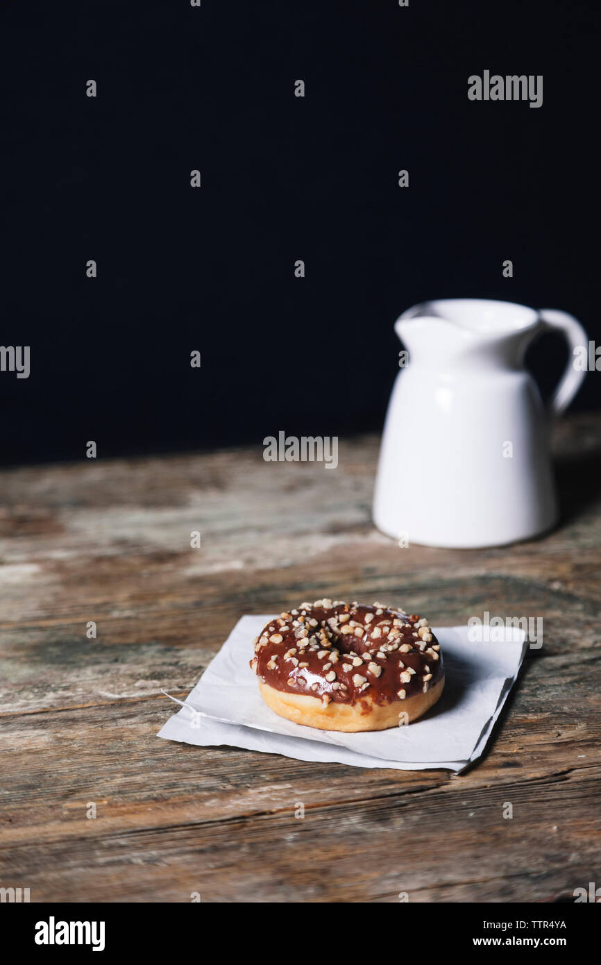 Schokolade Donut mit Wachspapier und Getränk auf Holztisch Schokolade Donut mit Wachspapier und Getränk auf Holztisch