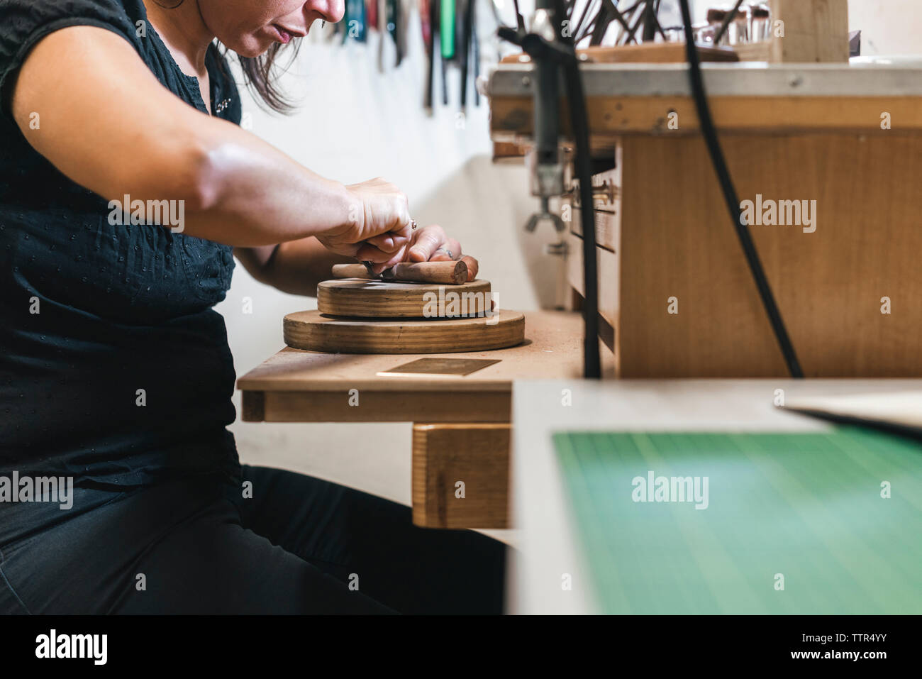 Mittelteil der weiblichen handwerkliche Herstellung von Schmuck auf hölzernen Tisch in Werkstatt Stockfoto