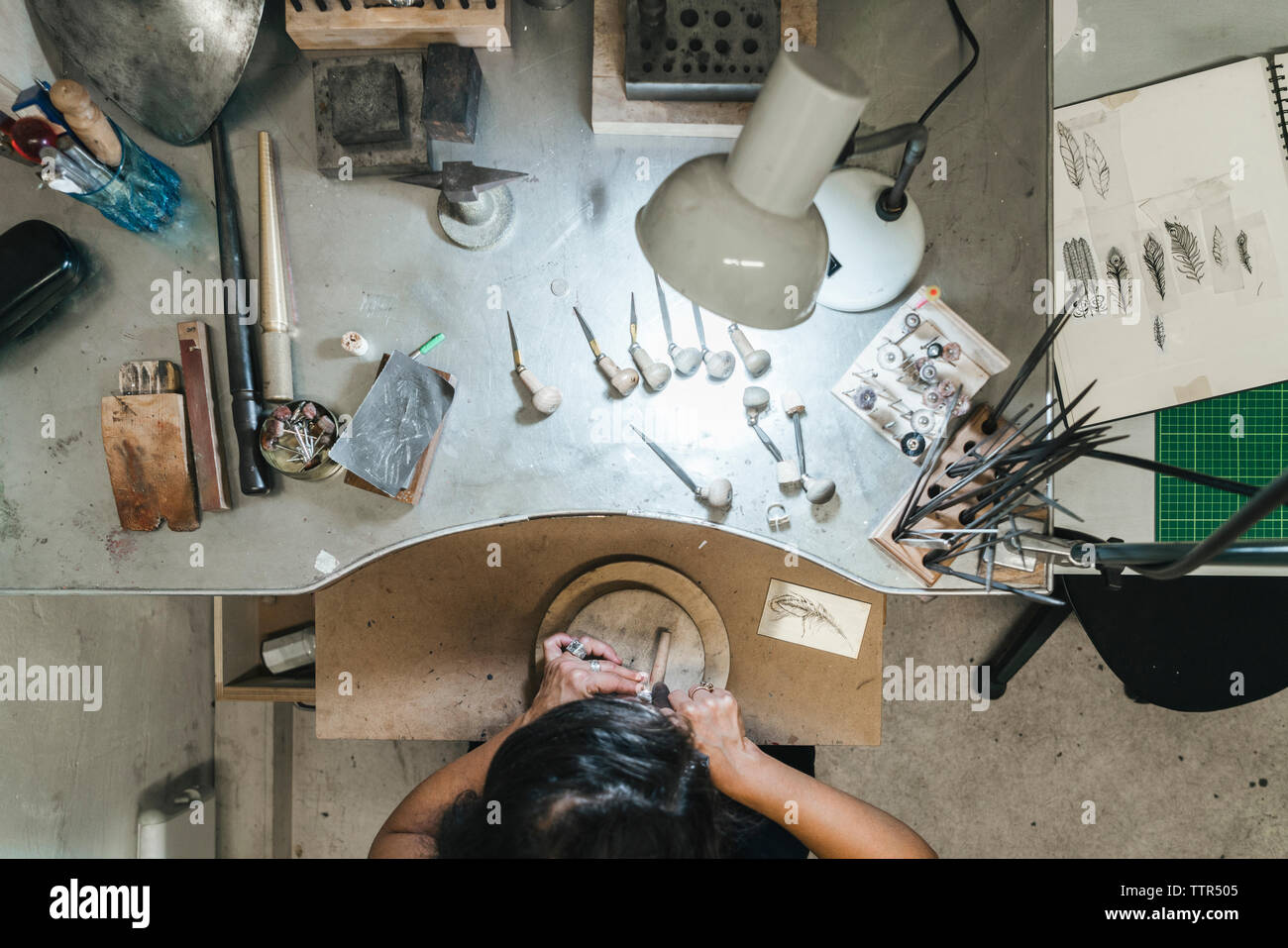 Hohe Betrachtungswinkel der weiblichen handwerkliche Herstellung von Schmuck auf hölzernen Tisch in Werkstatt Stockfoto