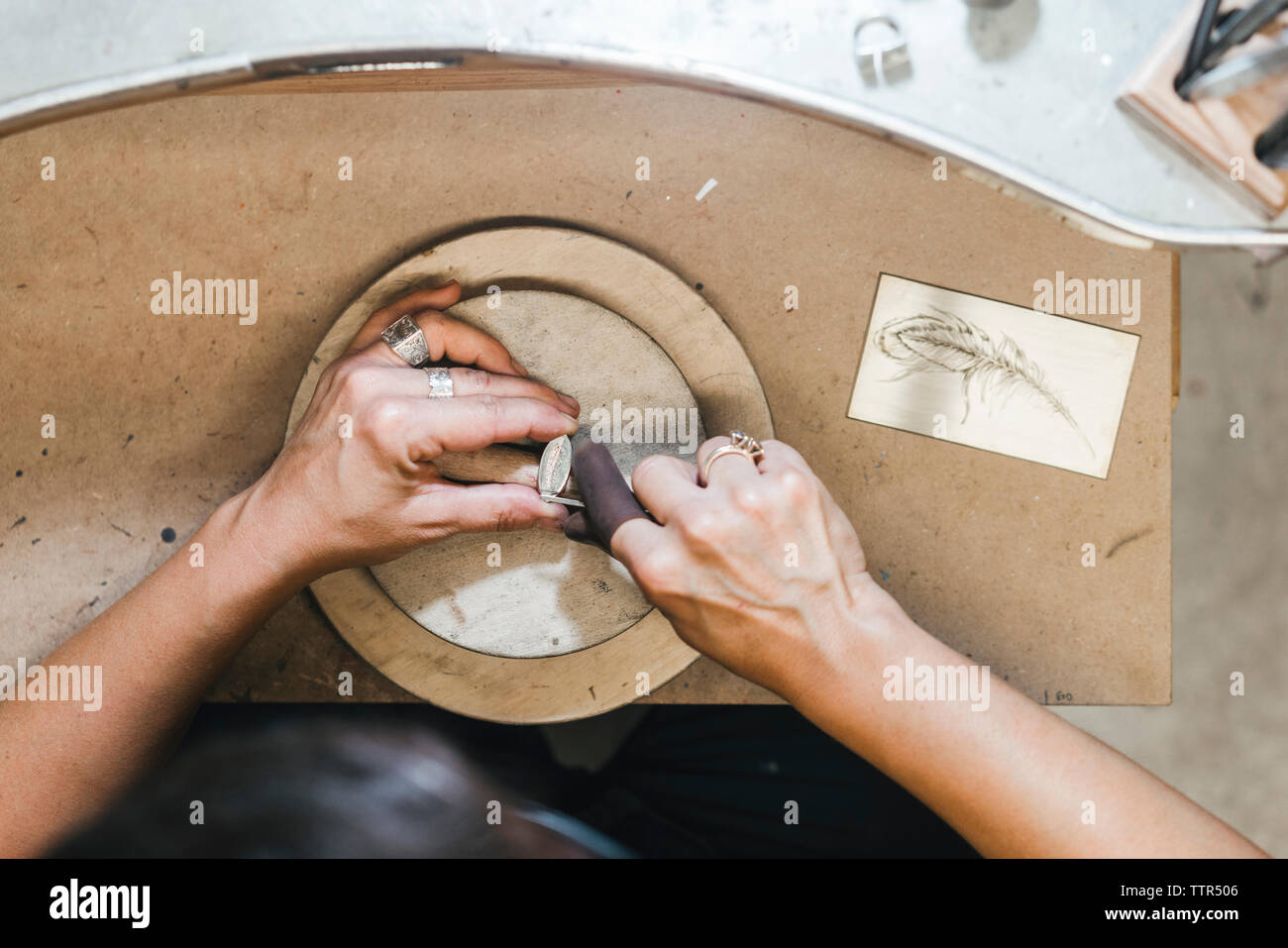 7/8 Hände der weiblichen handwerkliche Herstellung von Schmuck auf hölzernen Tisch in Werkstatt Stockfoto