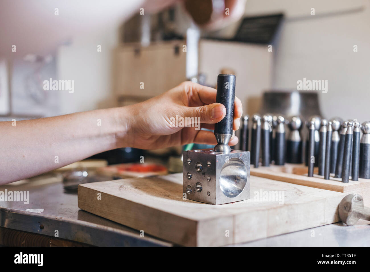 7/8 Händen der Handwerker mit Handwerkzeugen während Herstellung von Schmuck am Tisch in der Werkstatt Stockfoto