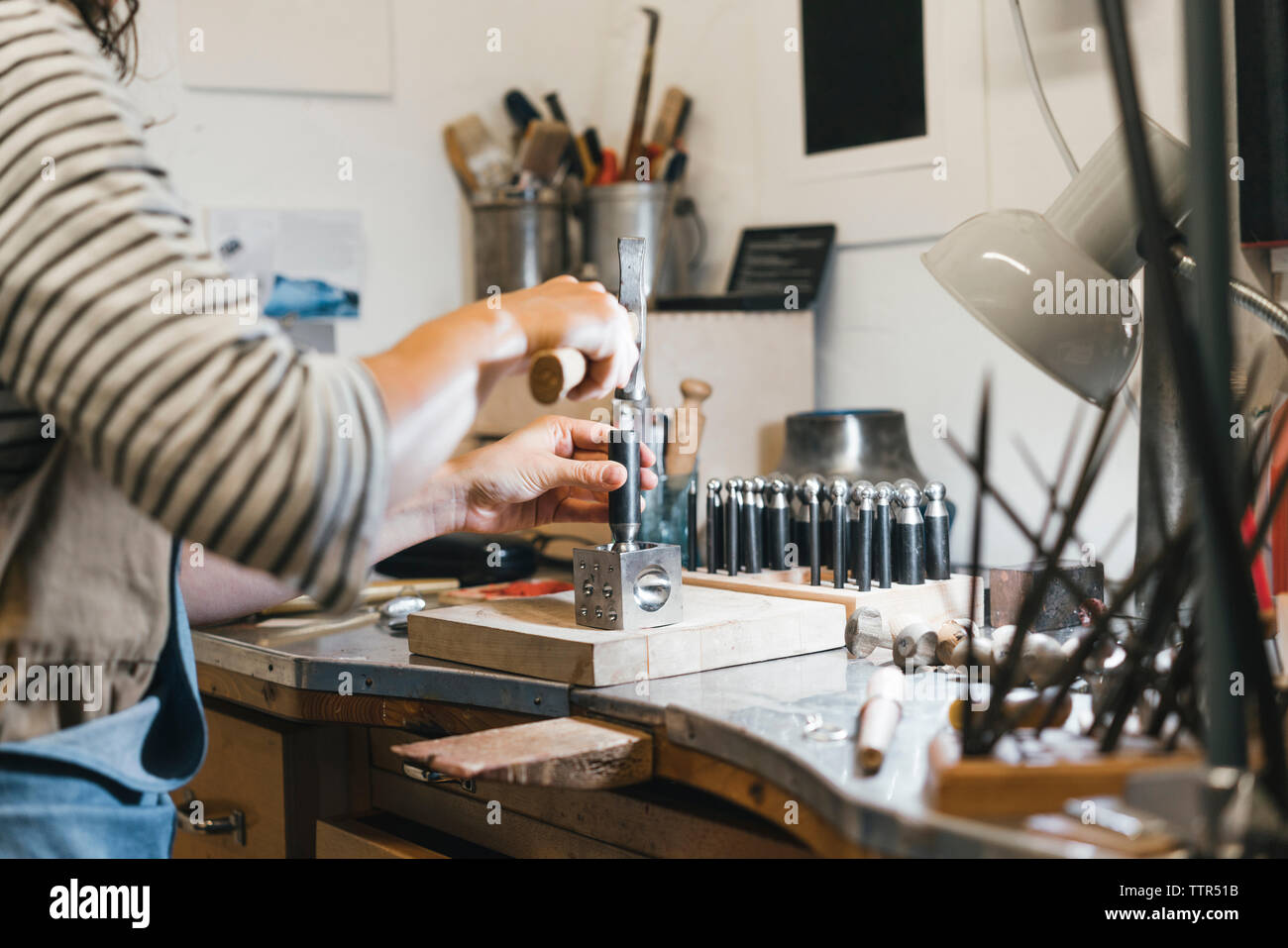 Mittelteil der Artisan mit Handwerkzeugen während Herstellung von Schmuck am Tisch in der Werkstatt Stockfoto