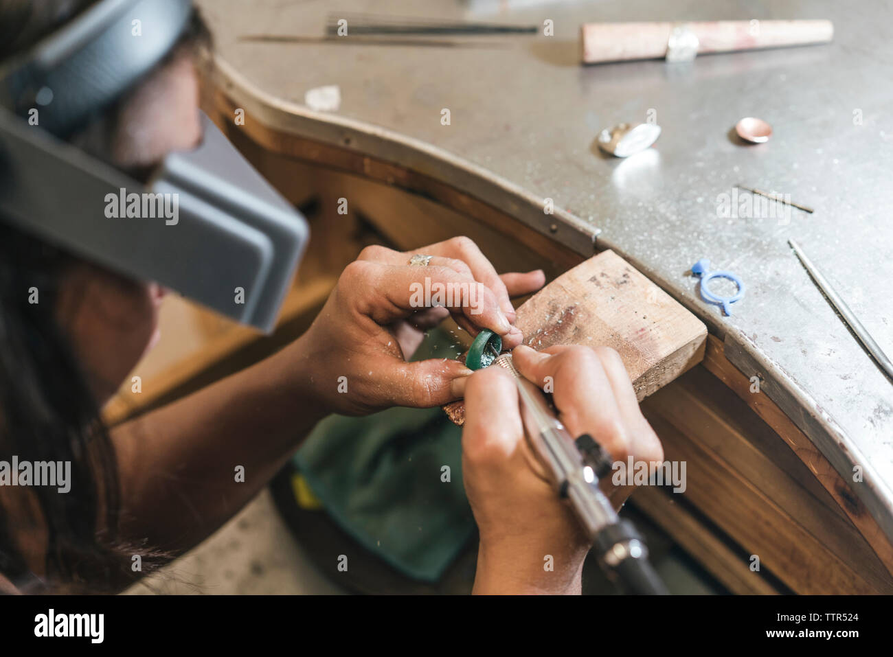 Hohe Betrachtungswinkel der weiblichen handwerkliche Gestaltung Ring mit Ausrüstung auf dem Tisch in der Werkstatt Stockfoto
