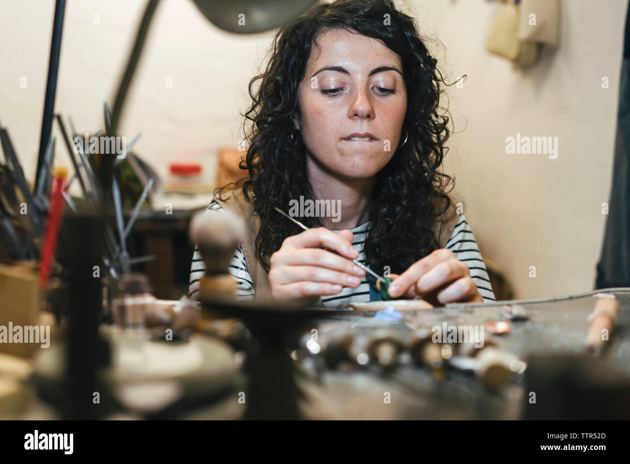 Mittelteil der weiblichen artisan, Ring, beim Sitzen am Tisch in der Werkstatt Stockfoto