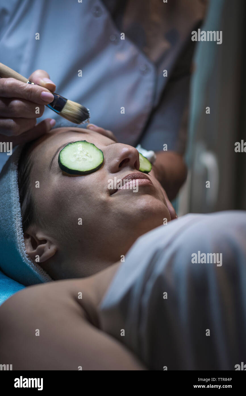 Mittelteil der Kosmetikerin, die Gesichtsmaske für weibliche Kunden bei Aesthetic Center Stockfoto