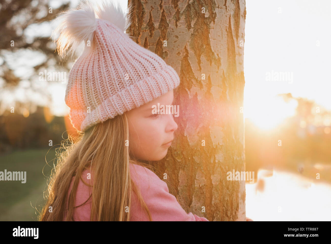 Junge Mädchen umarmt Baum im Park von sunst Stockfoto