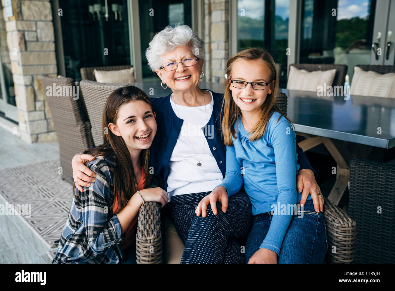 Portrait von Großmutter mit Enkelinnen sitzen auf der Veranda Stockfoto
