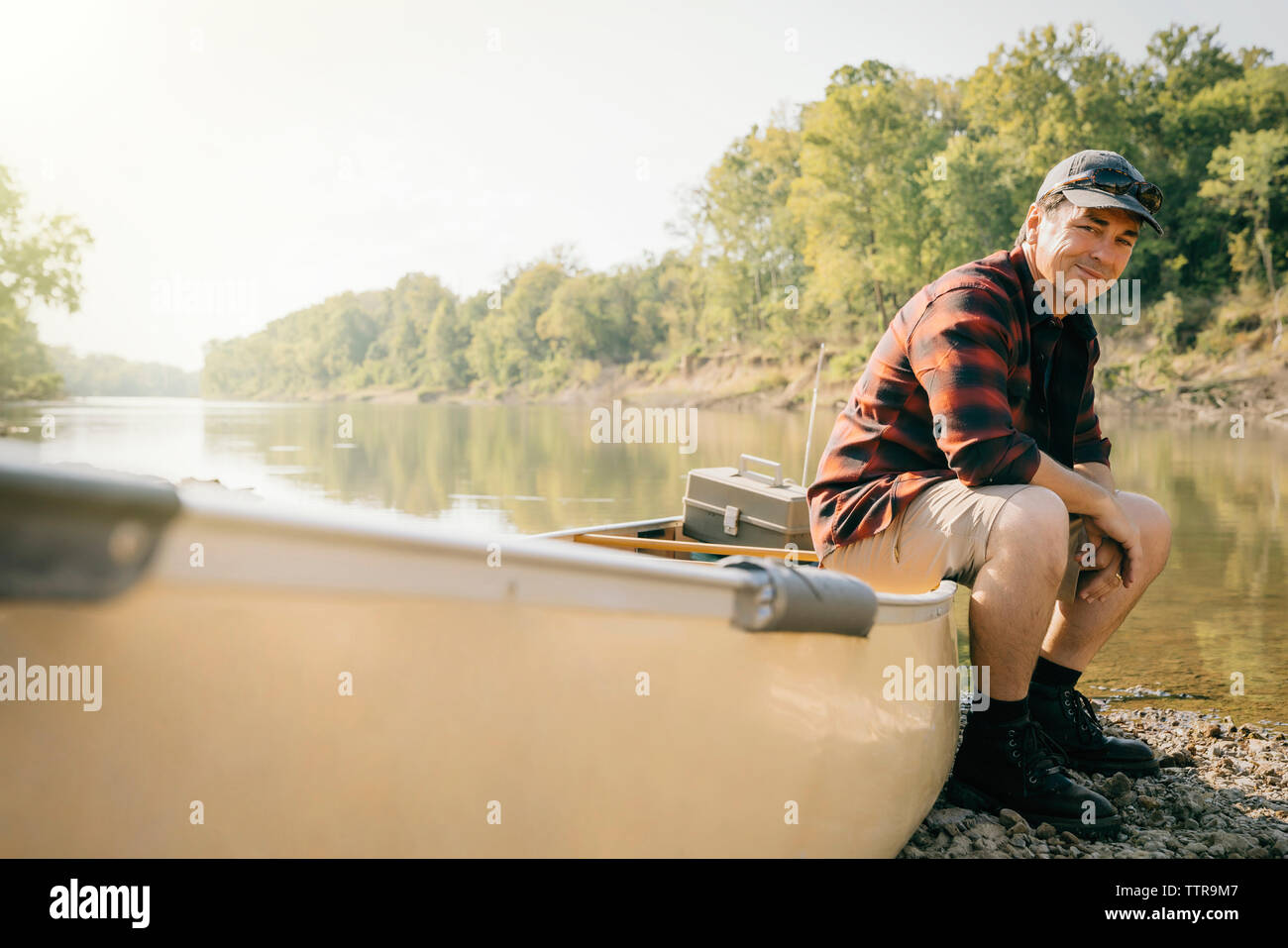 Portrait von lächelnden Mitte erwachsener Mann sitzt auf dem Boot am Seeufer Stockfoto