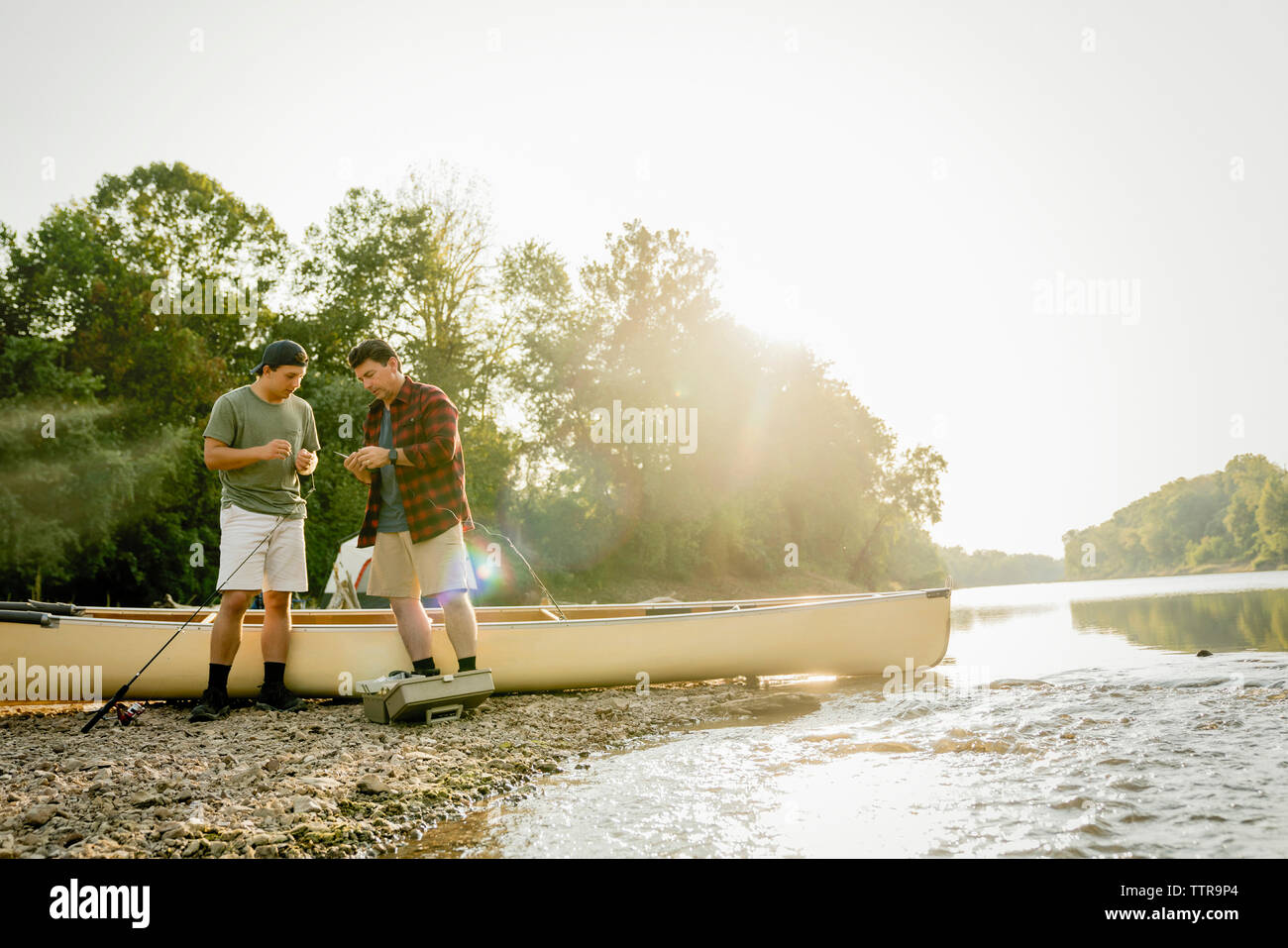 Männliche Freunde angeln Einstellen der Geräte, während mit dem Boot am Seeufer Stockfoto