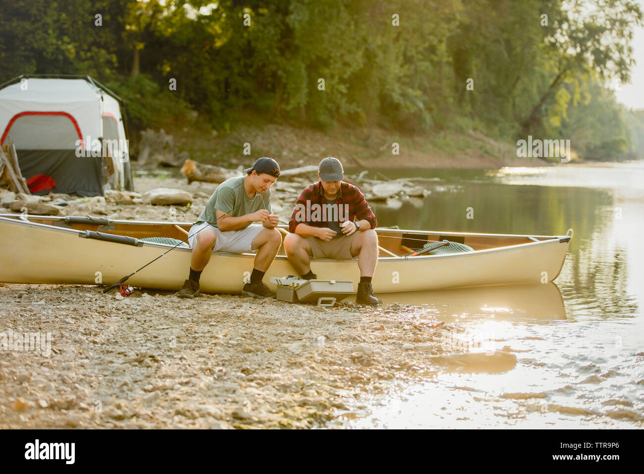 Freunde angeln Einstellen der Geräte, während auf dem Boot Camping sitzen Stockfoto