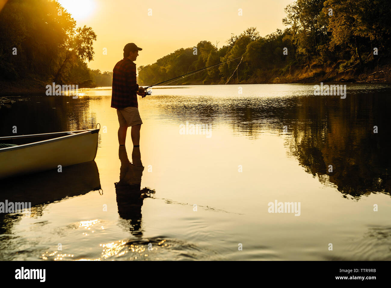 Seitenansicht des Mitte der erwachsene Mann angeln beim Stehen in der See bei Sonnenuntergang Stockfoto