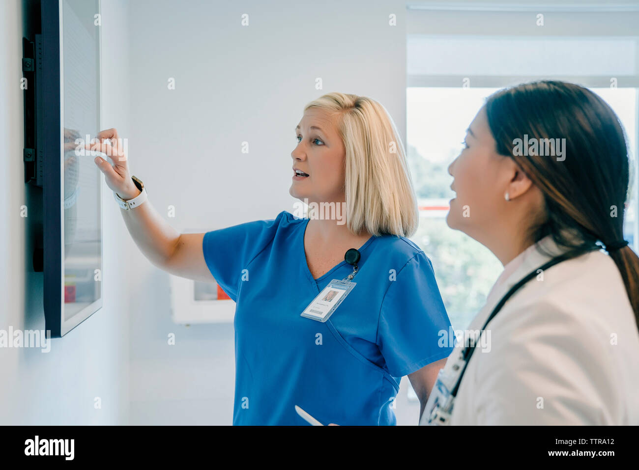 Ärztin auf Flachbildschirm während der Diskussion mit Kollegen im Krankenhaus Stockfoto