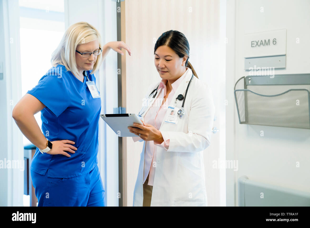 Weibliche Ärzte auf der Suche nach Tablet Computer, während durch die Wand im Krankenhaus ständigen Stockfoto