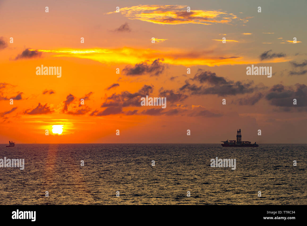 Fernsicht auf Bohrinsel im Meer gegen bewölkter Himmel bei Sonnenuntergang Stockfoto