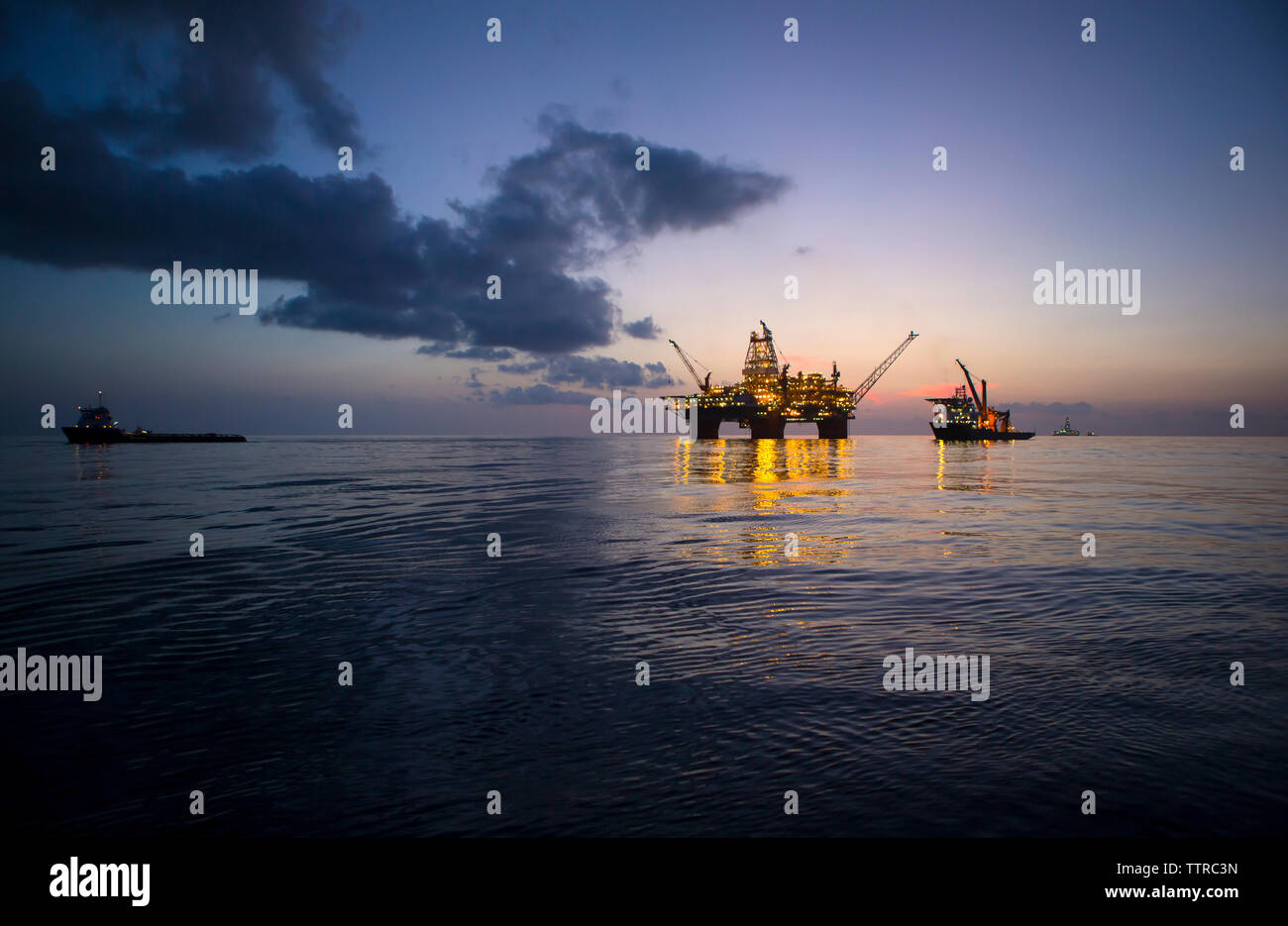 Beleuchtete Offshore Plattform gegen Himmel bei Dämmerung Stockfoto