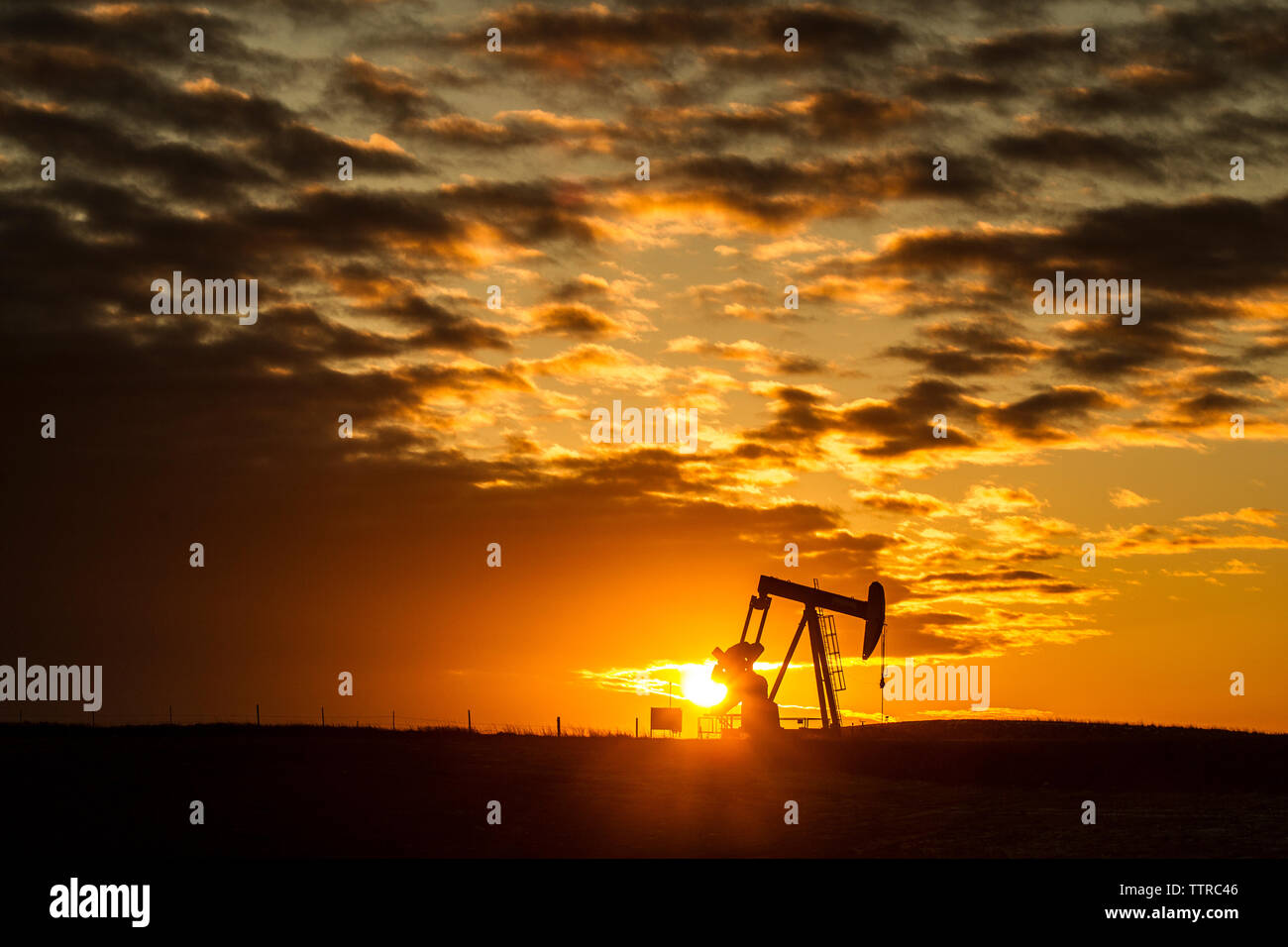Mitte der Abstand der Silhouette pumpjack am Öl Industrie gegen bewölkter Himmel bei Sonnenuntergang Stockfoto