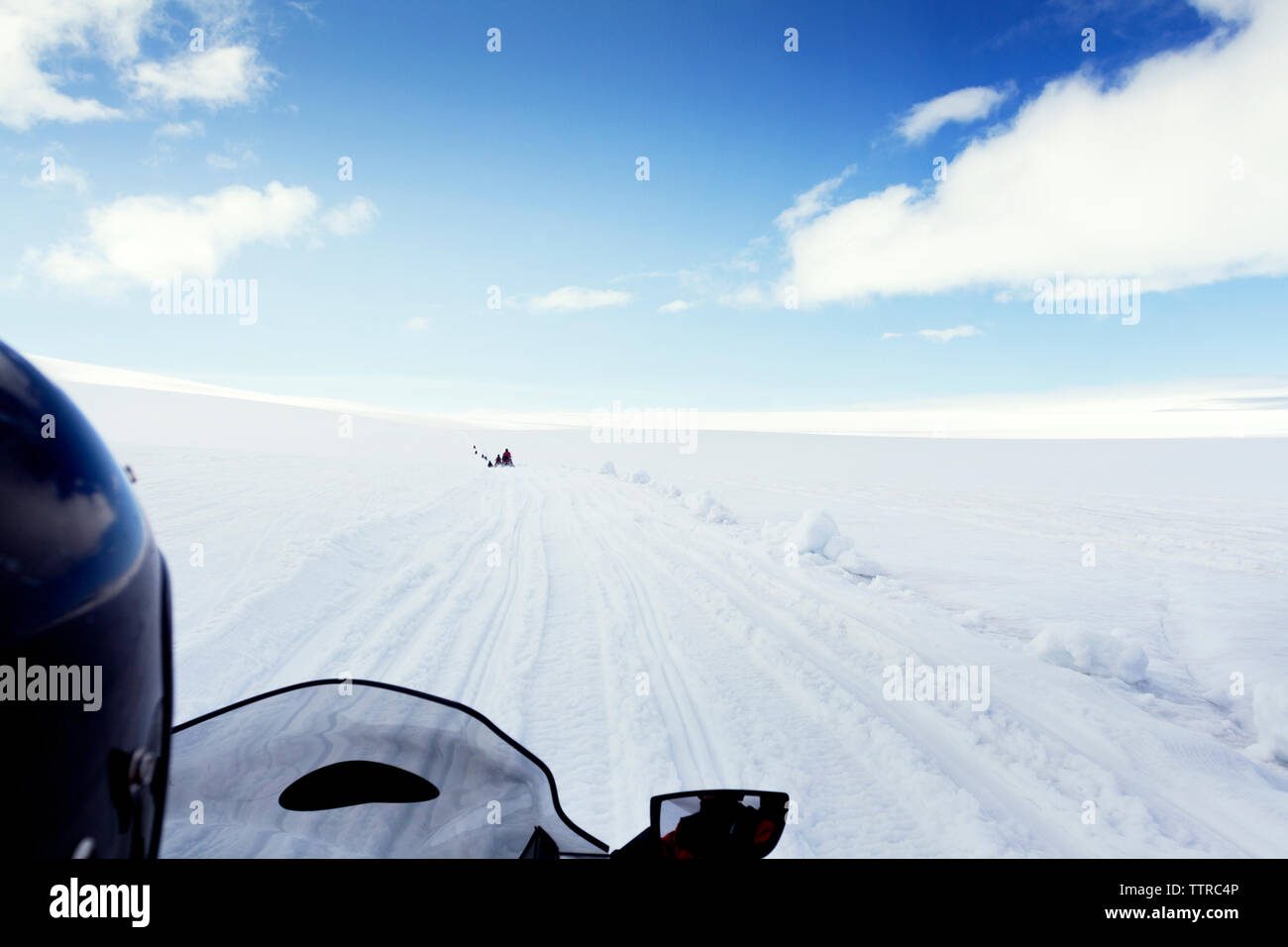 Zugeschnittenes Bild der Person reiten Schneemobil auf Landschaft gegen Sky Stockfoto