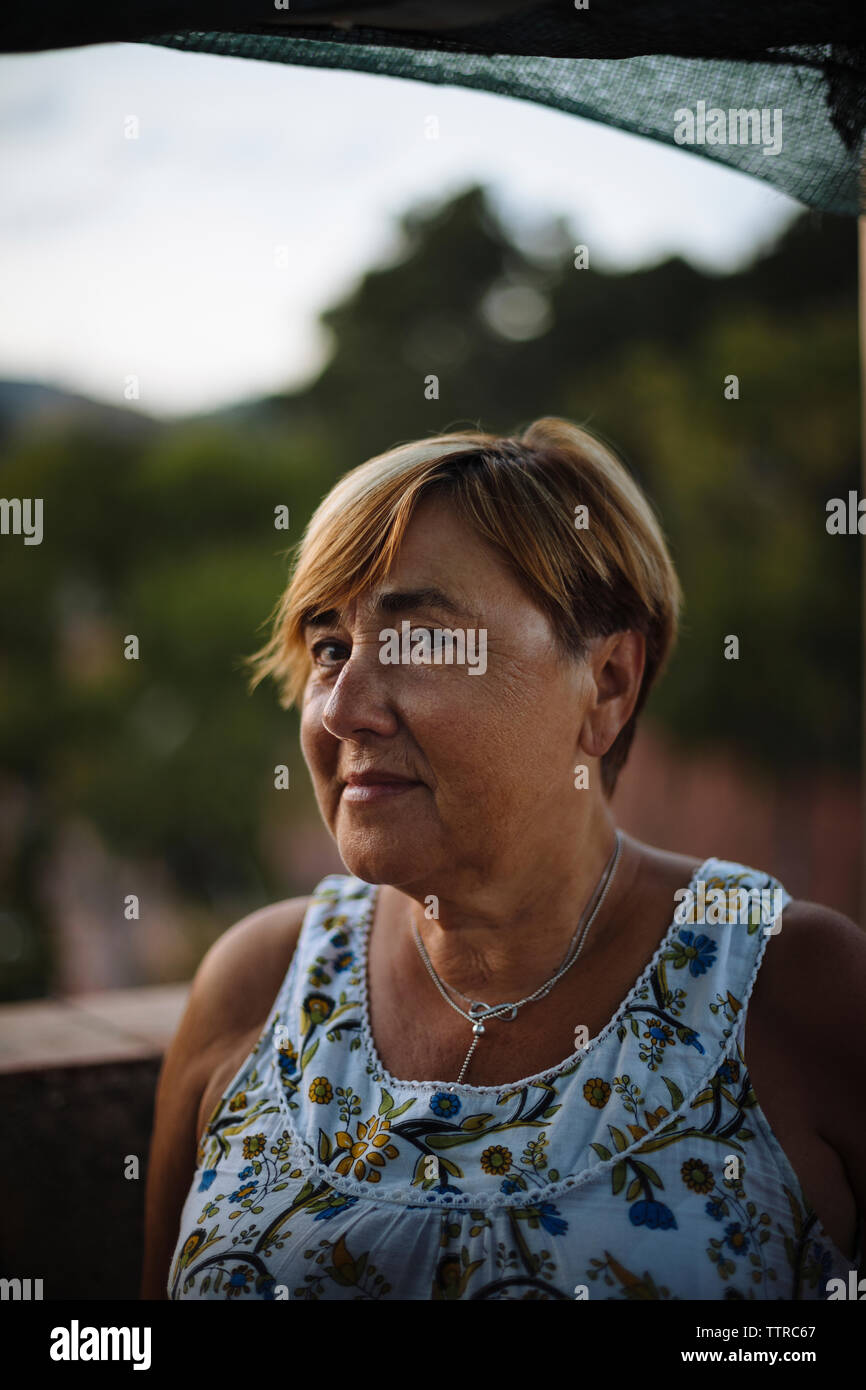 Nahaufnahme Porträt der älteren Frau mit kurzen Haaren auf Gebäude Terrasse bei Sonnenuntergang Stockfoto