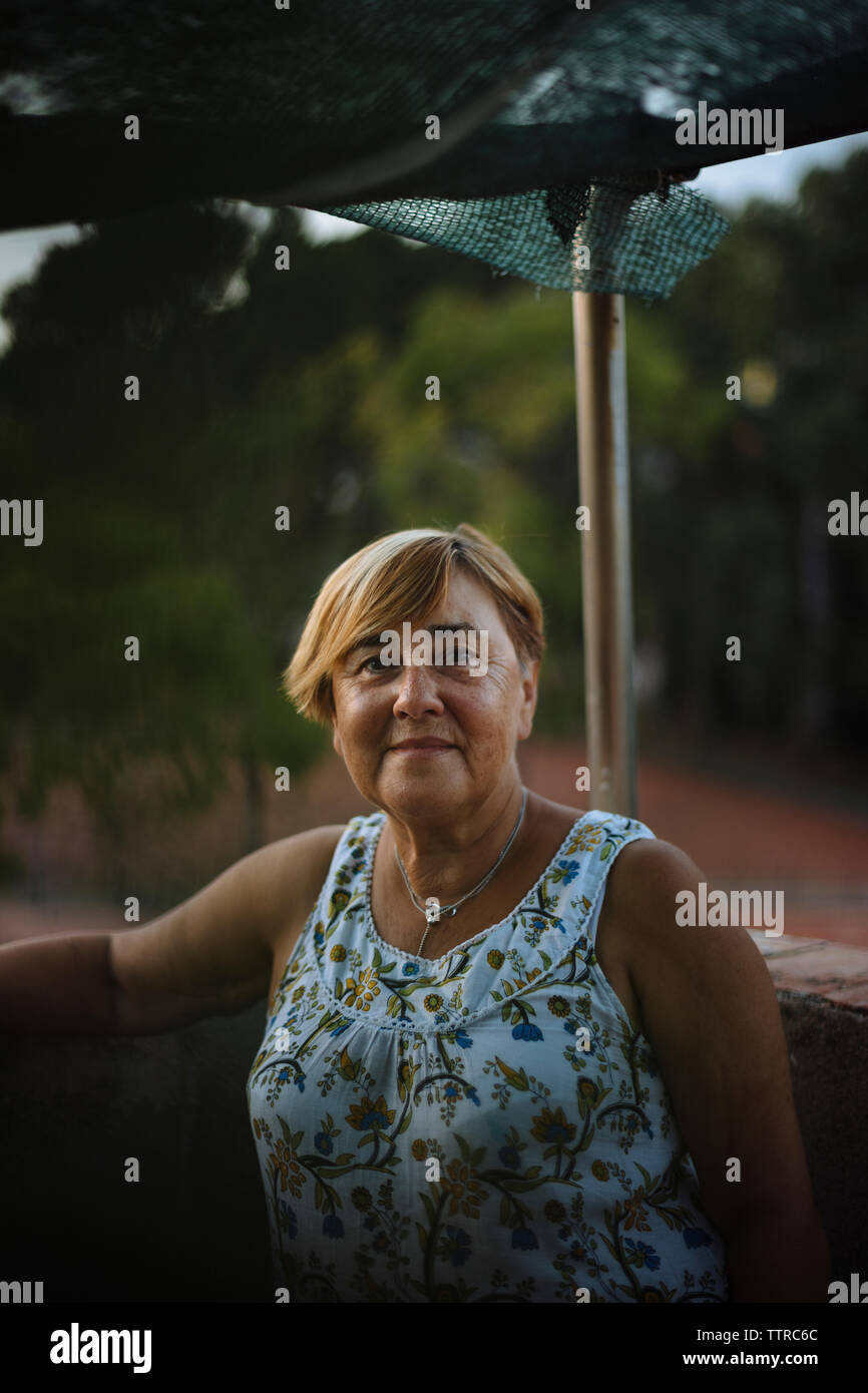Nahaufnahme Porträt der älteren Frau mit kurzen Haaren stehen durch Geländer auf Gebäude Terrasse Stockfoto