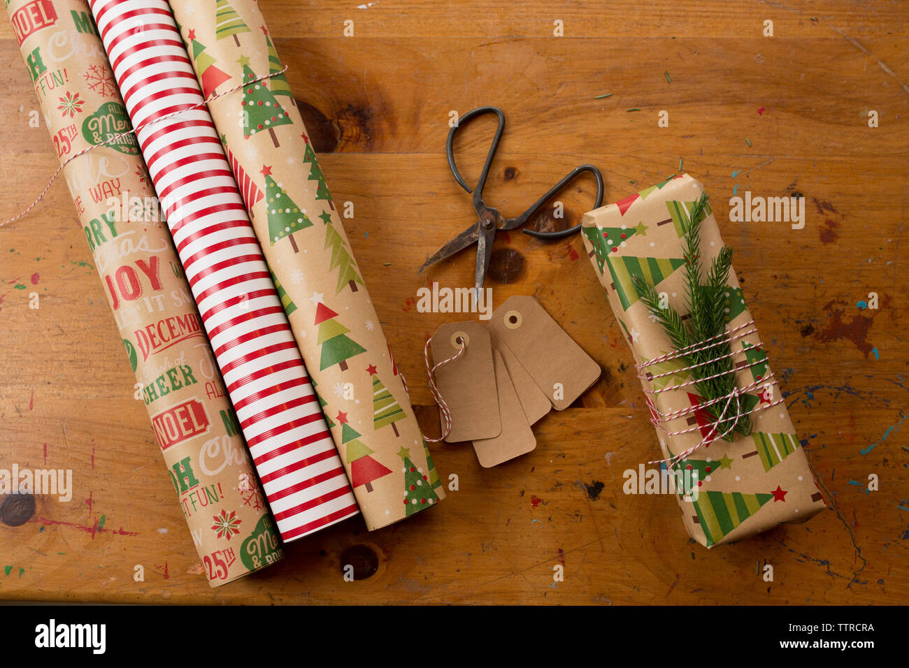 Nahaufnahme der Schere mit aufgerollten Geschenkpapieren und weihnachtsgeschenk auf dem Tisch Stockfoto