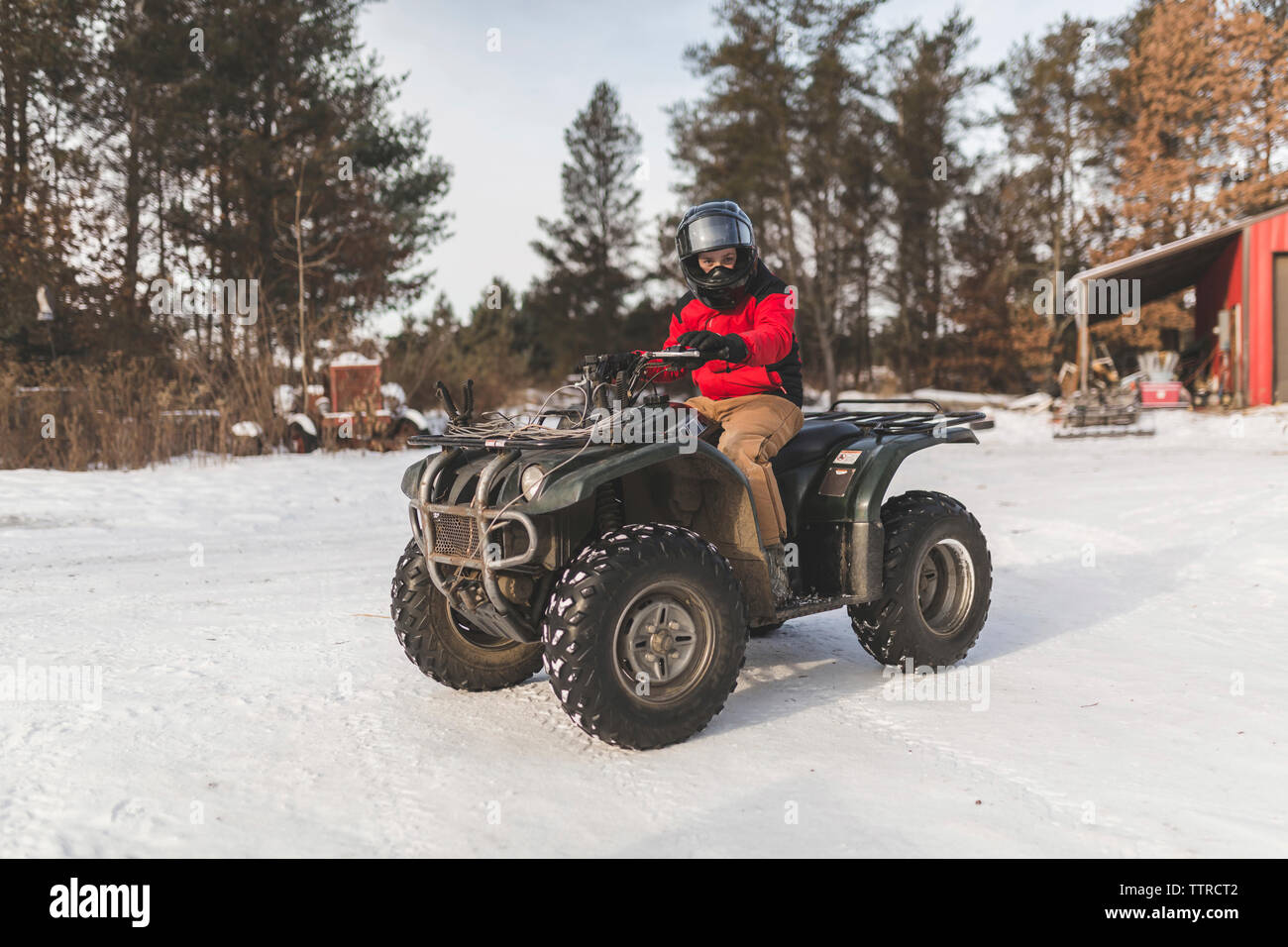 Teenager fahren Quad auf schneebedeckten Feld Stockfoto