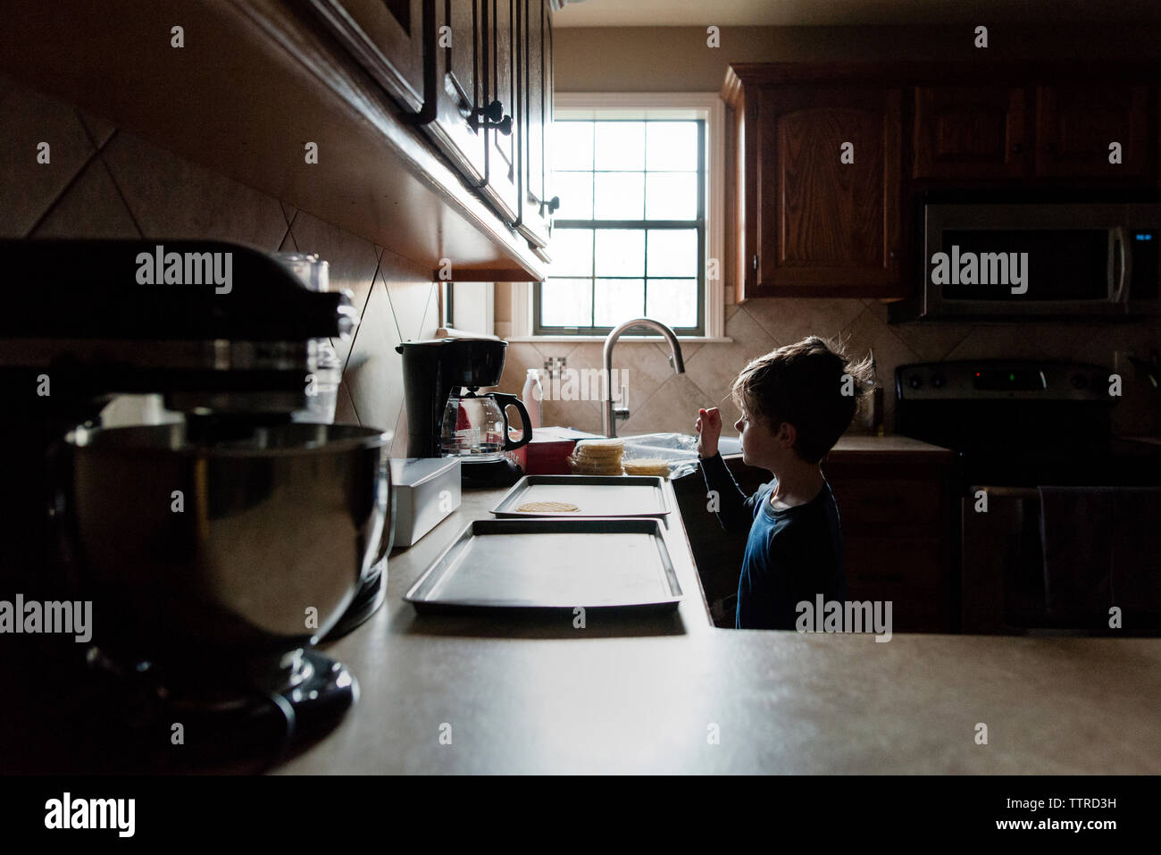 Junge Blick auf Waffel auf Fach beim Stehen in der Küche Stockfoto
