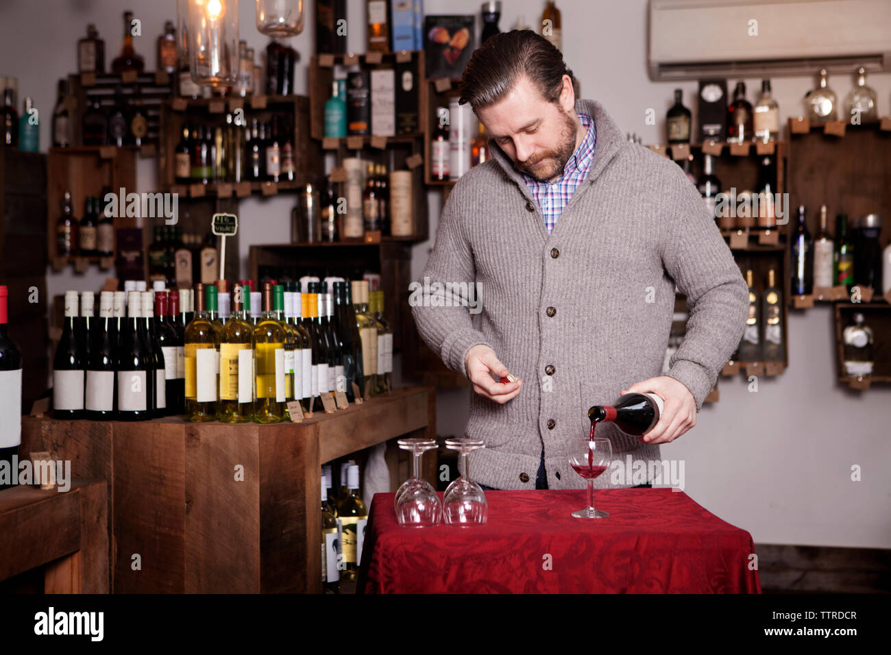 Männliche Sommelier gießen Rotwein in Glas Shop Stockfoto