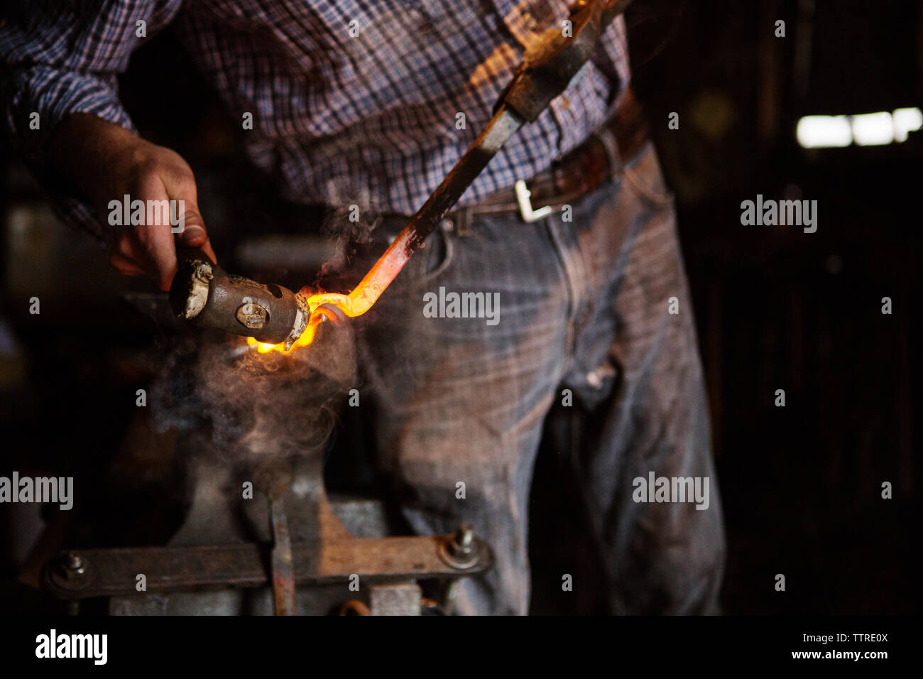 Mittelteil der Handwerker hämmern Metall im Werk Stockfoto