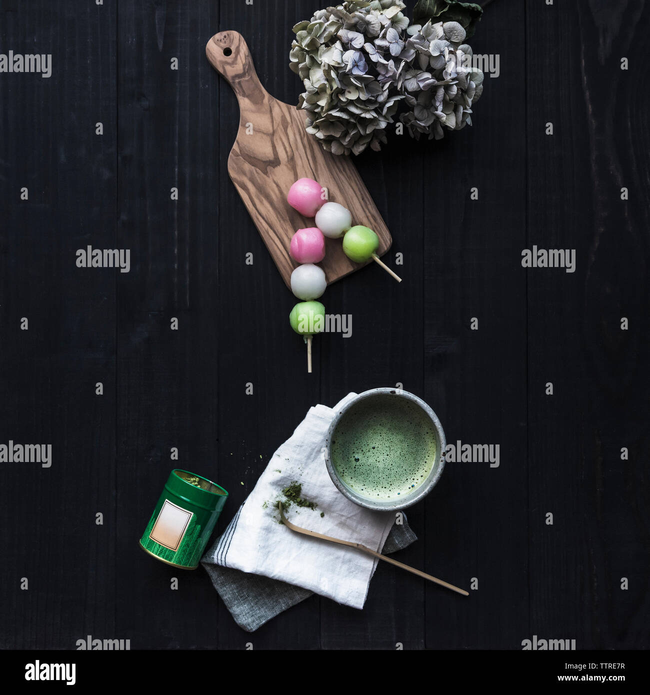 Ansicht von oben von Matcha Tee mit süßen Speisen und Hortensien auf schwarz Tabelle Stockfoto