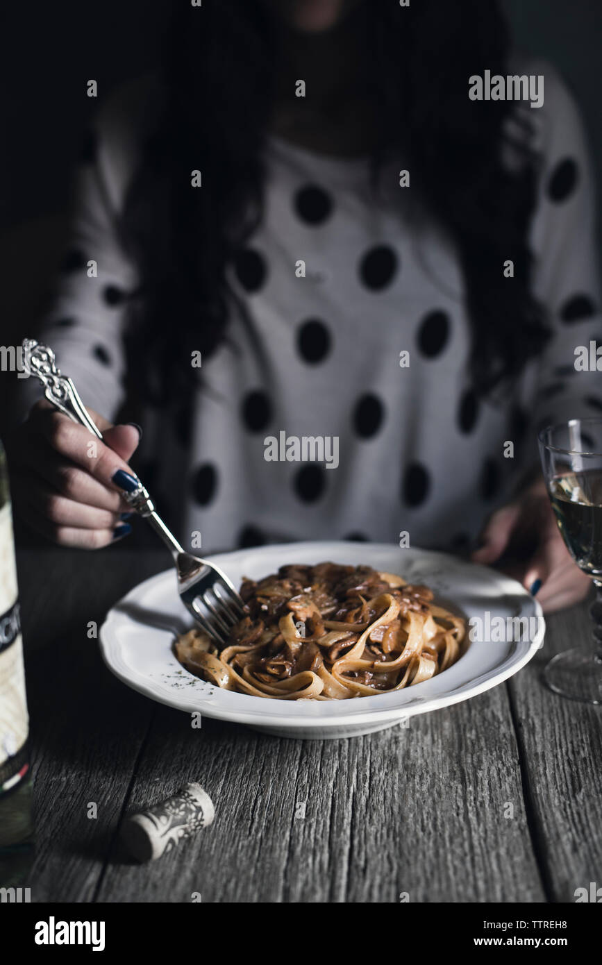 Mittelteil der Frau, Pasta, während bei Tisch sitzen Stockfoto