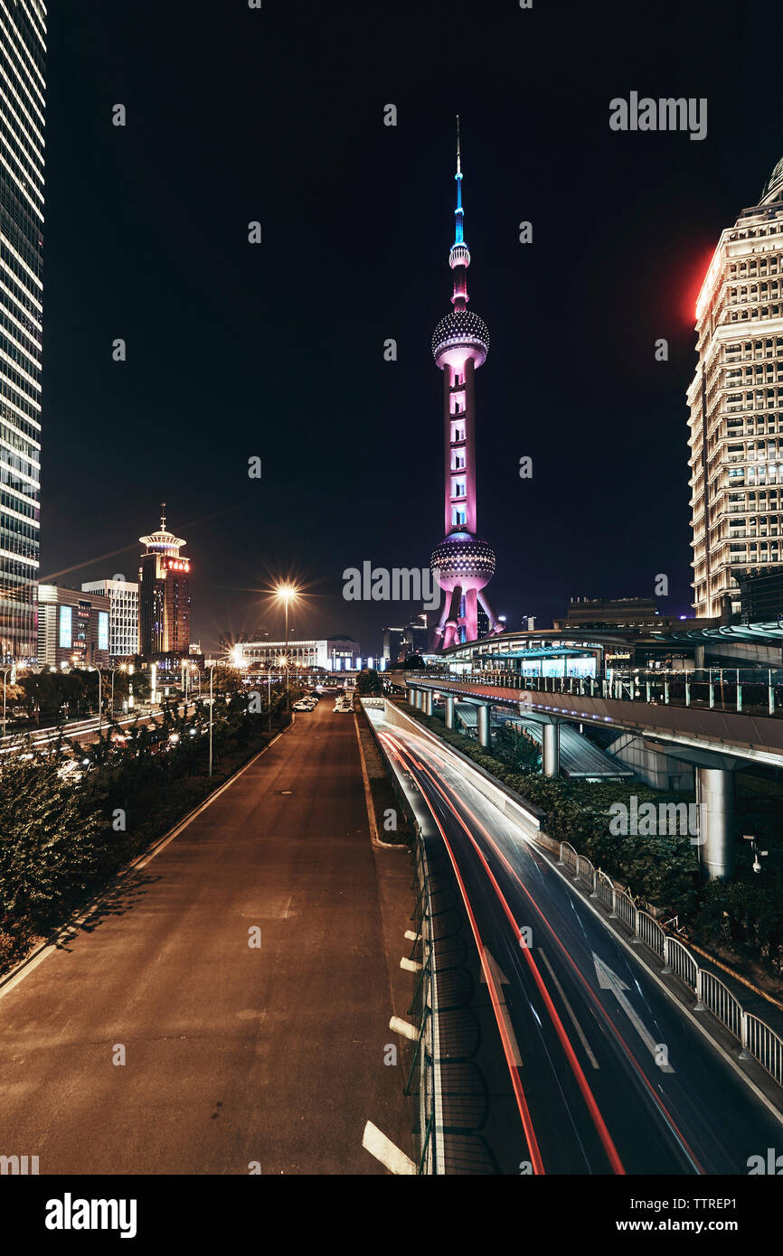 Leichte Wanderwege auf der Straße gegen Beleuchtete Oriental Pearl Tower in der Stadt bei Nacht Stockfoto