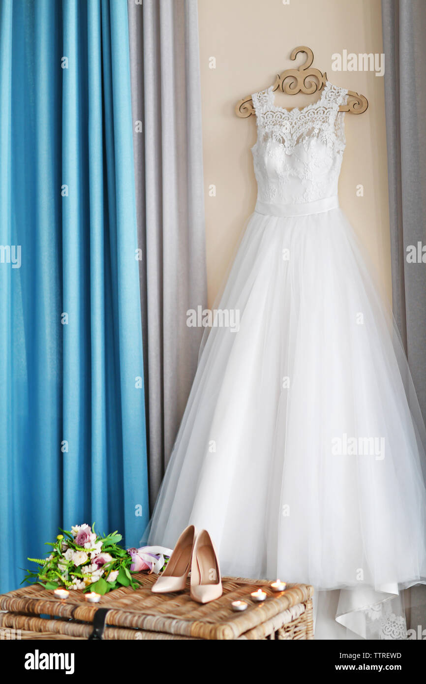 Schuhe auf wicker Brust und Hochzeit Kleid hängen an der Wand im Zimmer Stockfoto