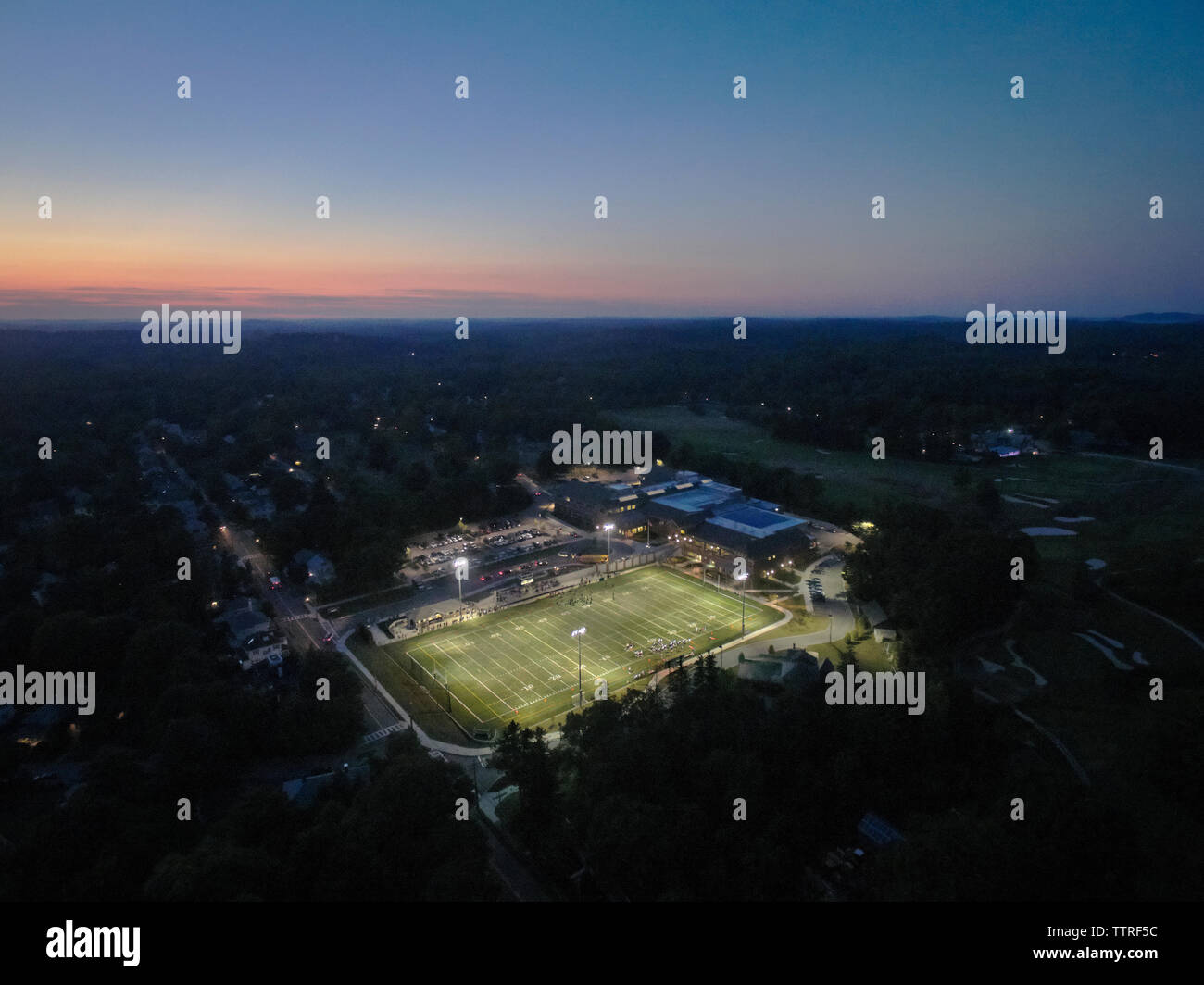 Luftaufnahme von beleuchteten Sportplatz und Bäume gegen den Himmel bei Sonnenuntergang Stockfoto