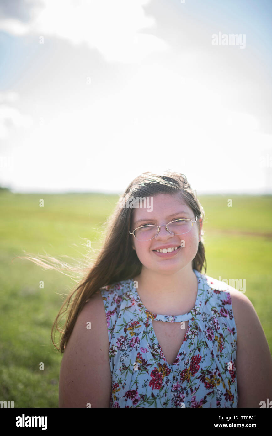 Portrait von übergewichtigen Teenager Mädchen lächelnd auf Feld gegen Himmel im Sommer Stockfoto